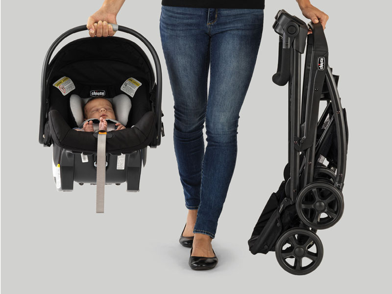 From left to right: Baby in KeyFit carseat, woman's legs, keyfit caddy folded up.