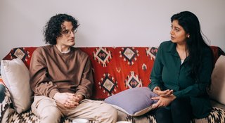 Two people sitting on a sofa talking