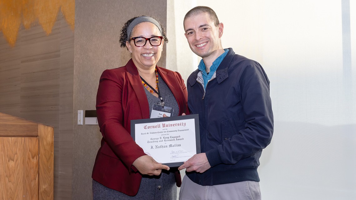 Dean of Faculty Eve De Rosa and Matias hold award certificate and smile at camera