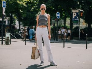 blonde woman wearing white jeans and cropped halter top and sunglasses standing in the street