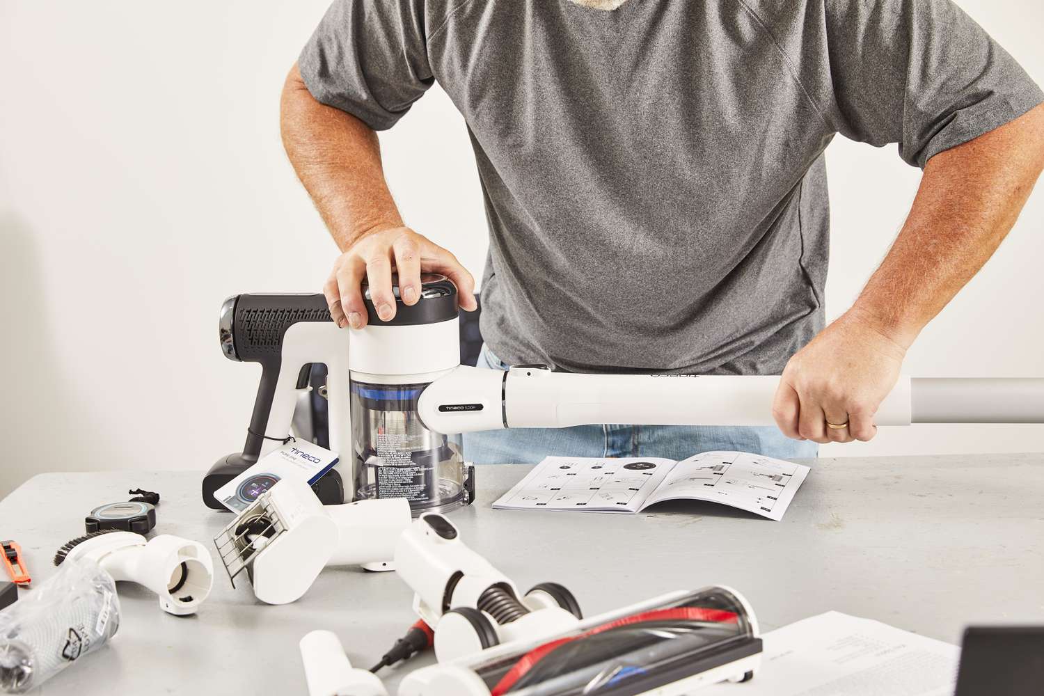 Person assembling the Tineco Pure One S15 Pro Cordless Stick Vacuum Cleaner on a table during product testing