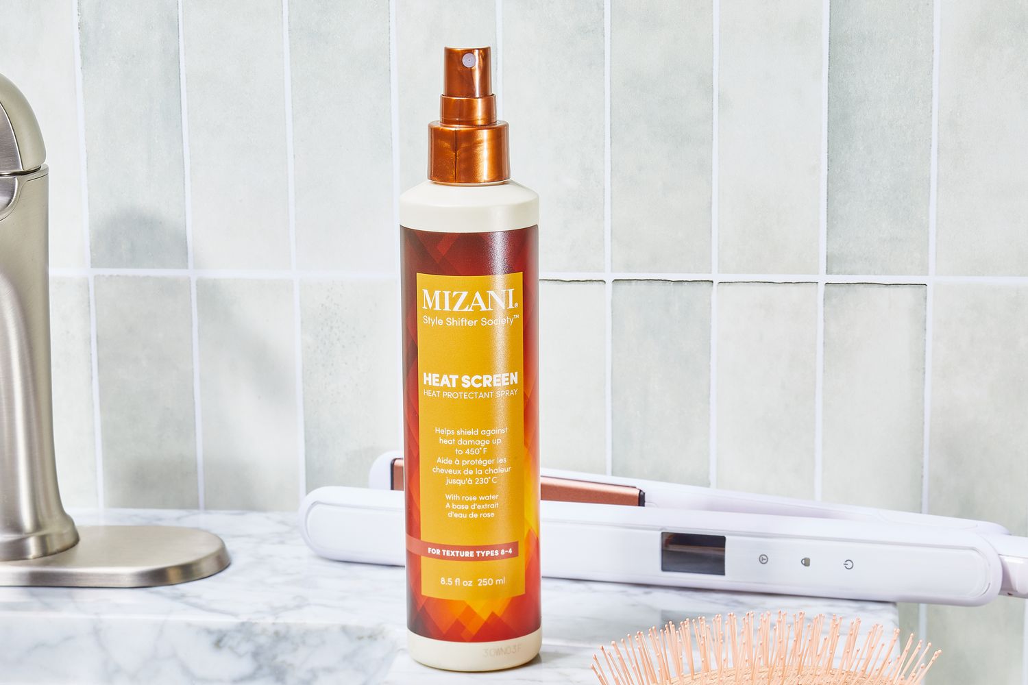 Mizani Heat Screen Hair Protectant Spray bottle sits on bathroom counter with hair styling tools