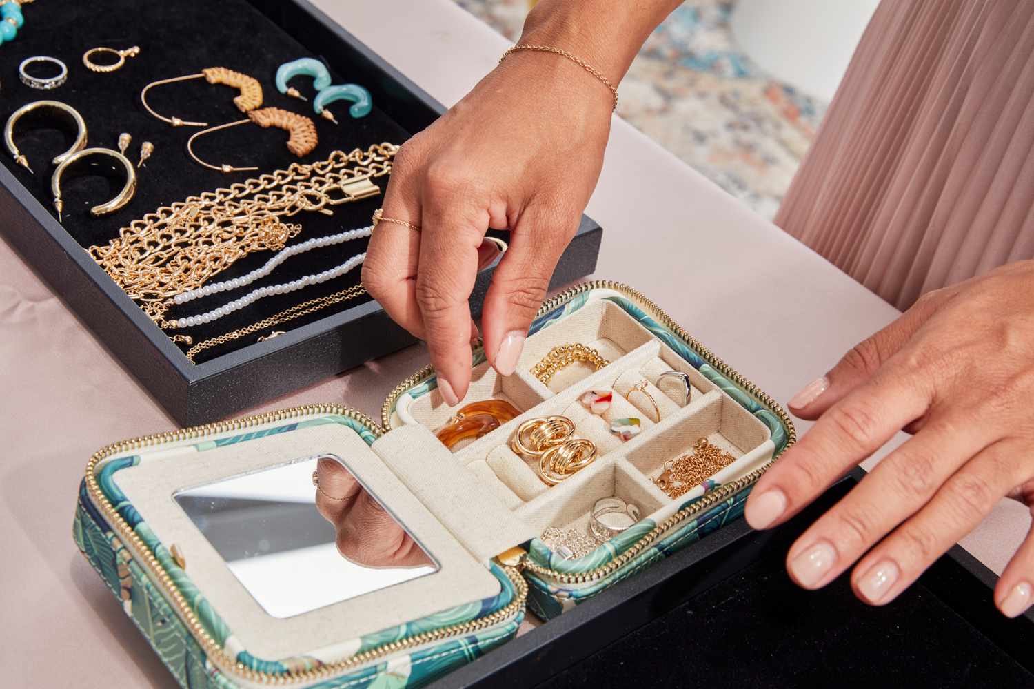 A person putting jewelry into the Mark & Graham Small Travel Jewelry Case.