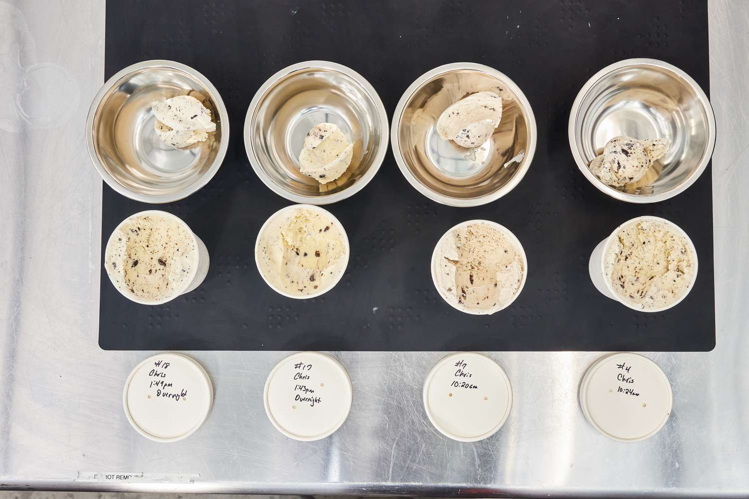 Four different ice creams from different ice cream makers shown scooped from paper containers into bowls. 