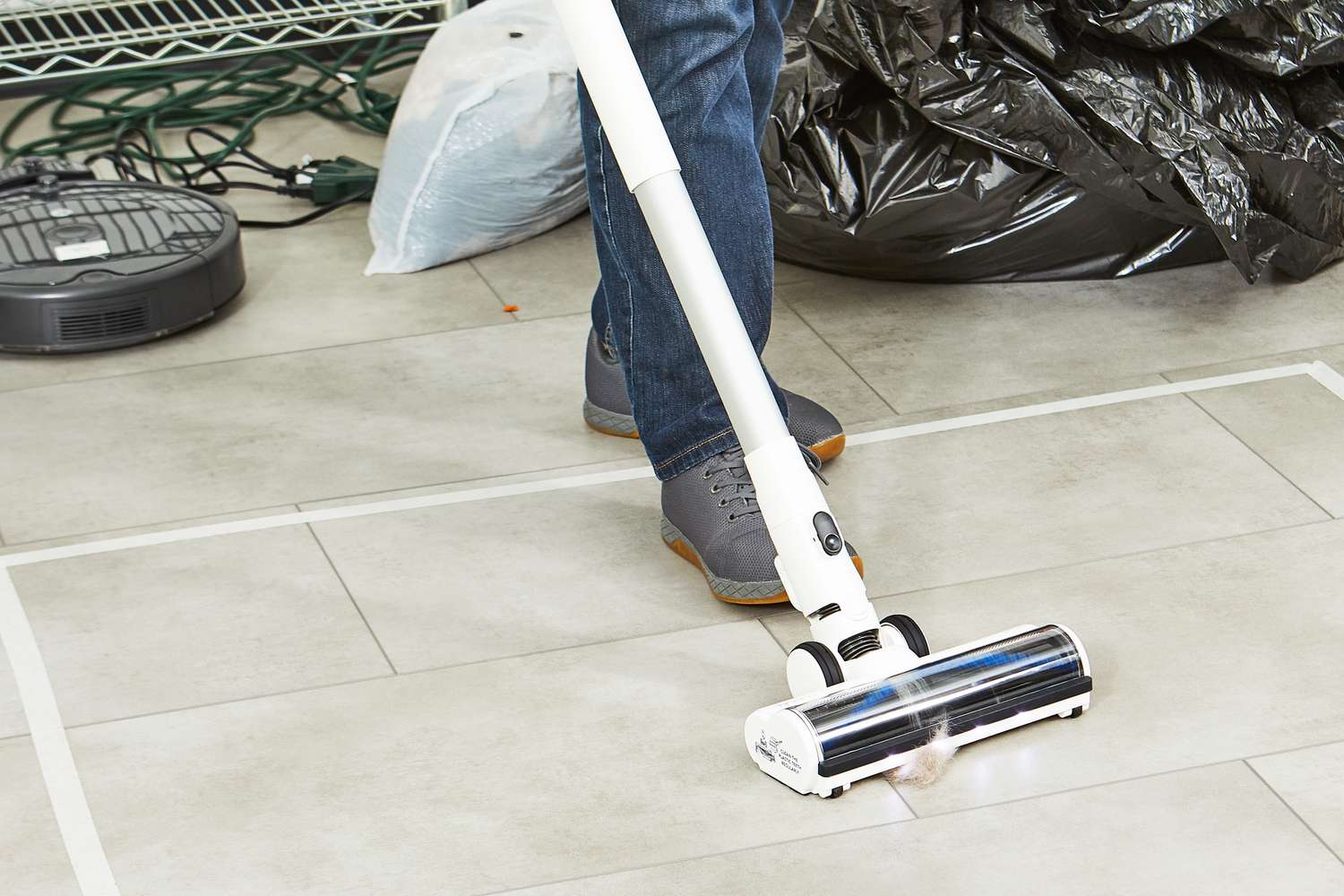 person vacuums hair off tile floor