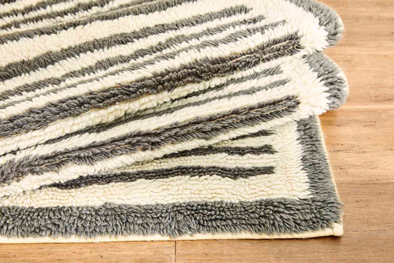 The AllModern Machine Washable Hand-Woven Wool Ivory/Charcoal Area Rug folded up