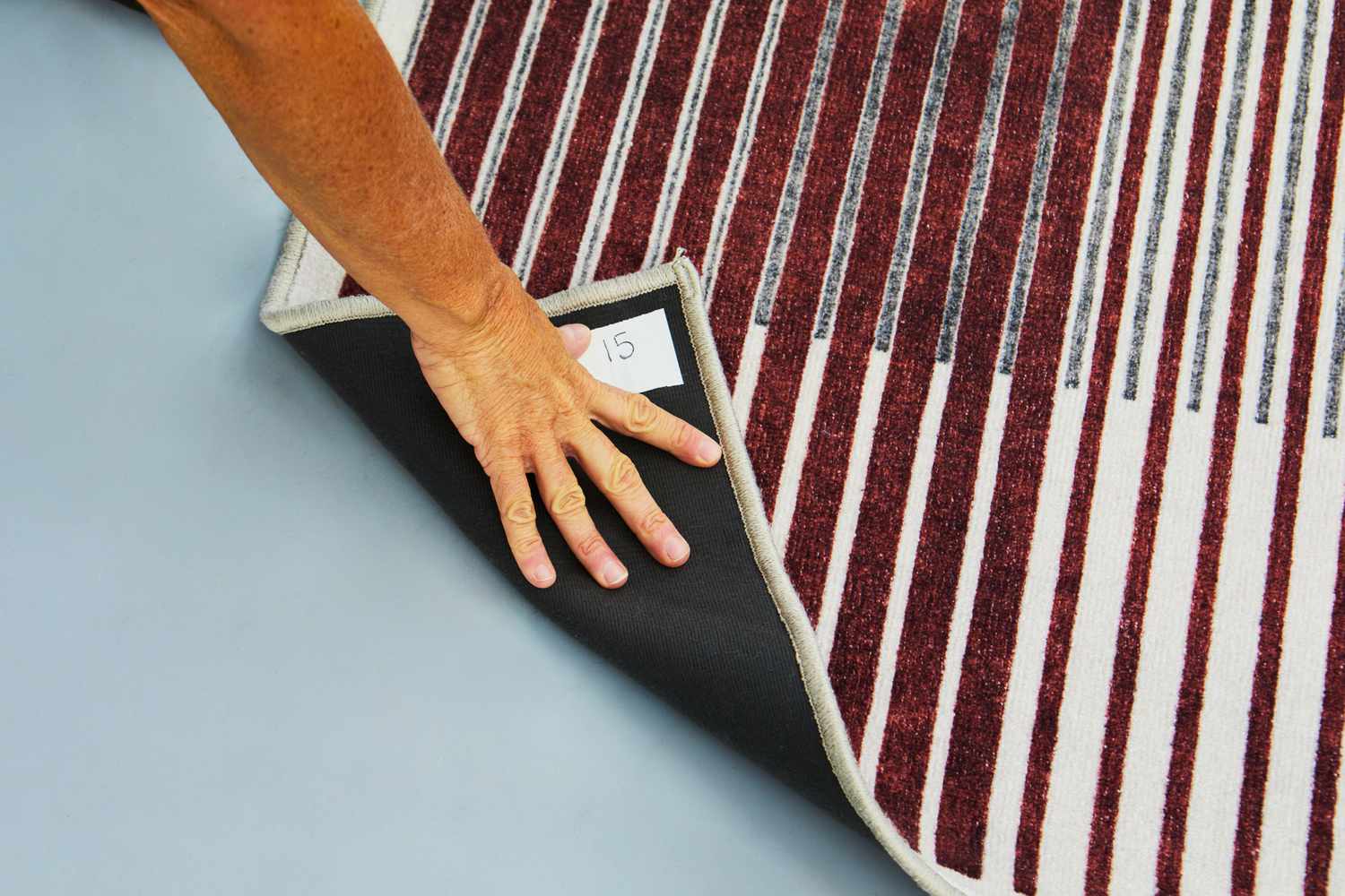 A person lifting up one side of the Ruggable Gradasi Premium Rug