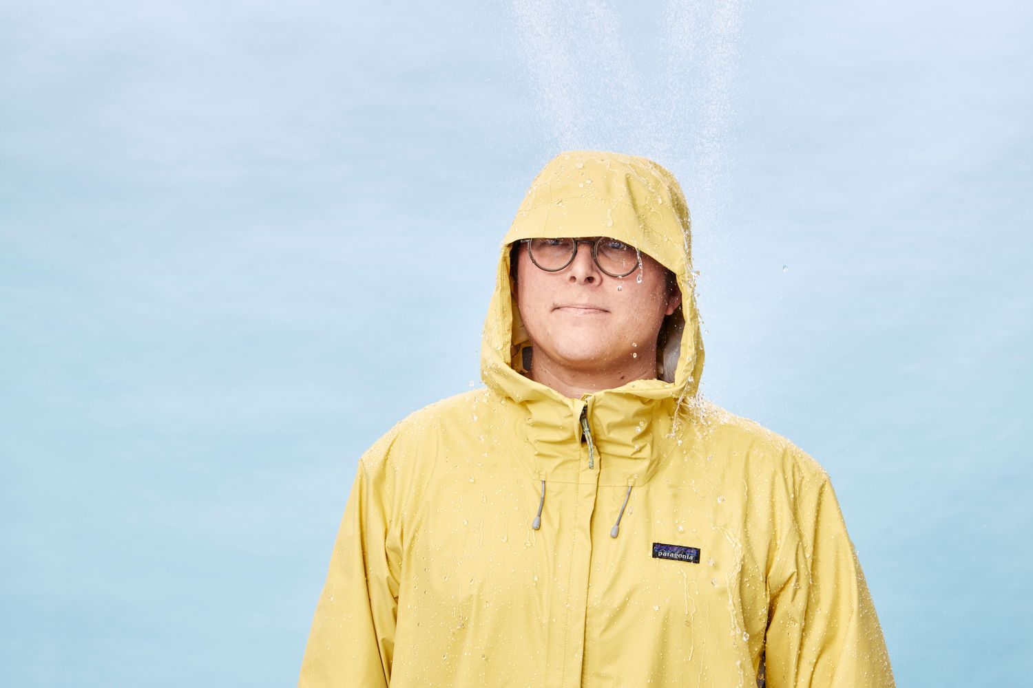 Water pouring on hood of Patagonia Men's Torrentshell 3L while man is wearing it