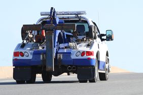 Rear quarter view of a nondescript tow truck travelling on a highway.