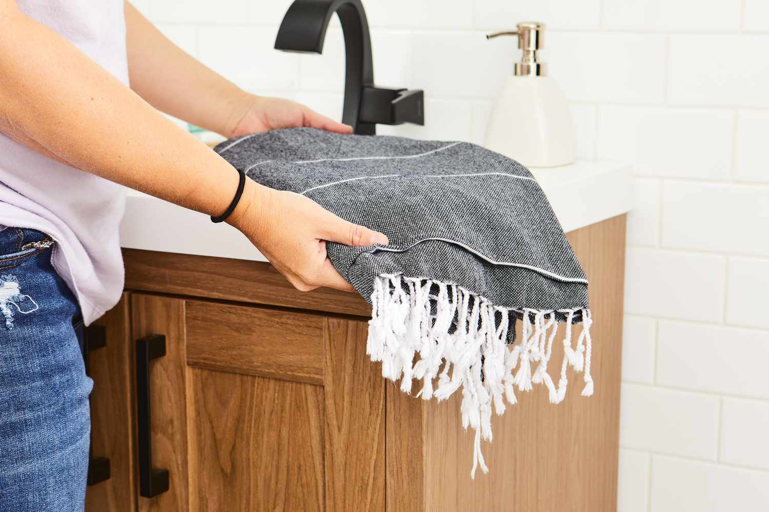 Person folding Cacala 100% Organic Cotton Pestemal Turkish Bath Towel on sink