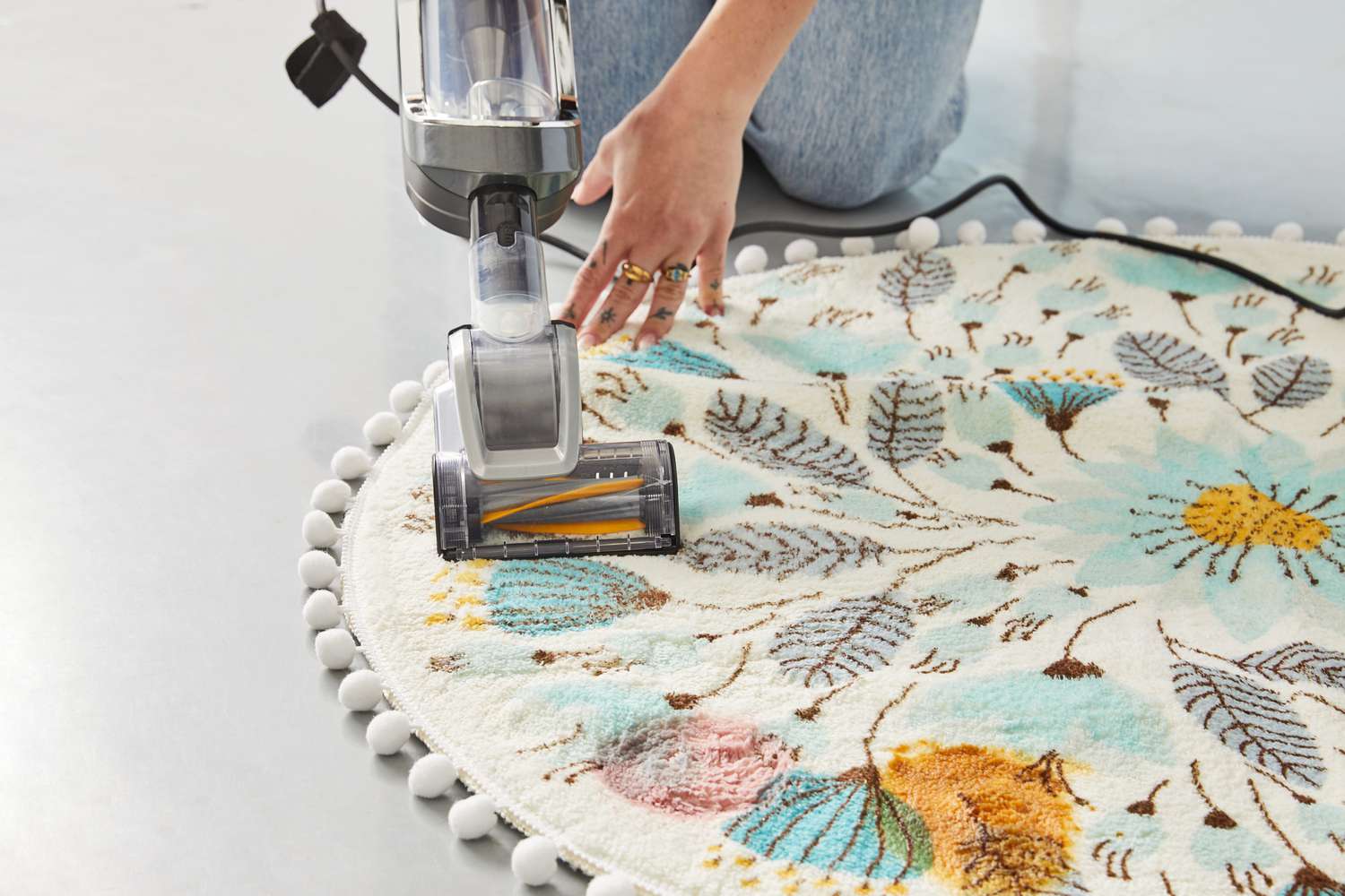 A person vacuuming the Uphome Pom Pom Round Floral Rug