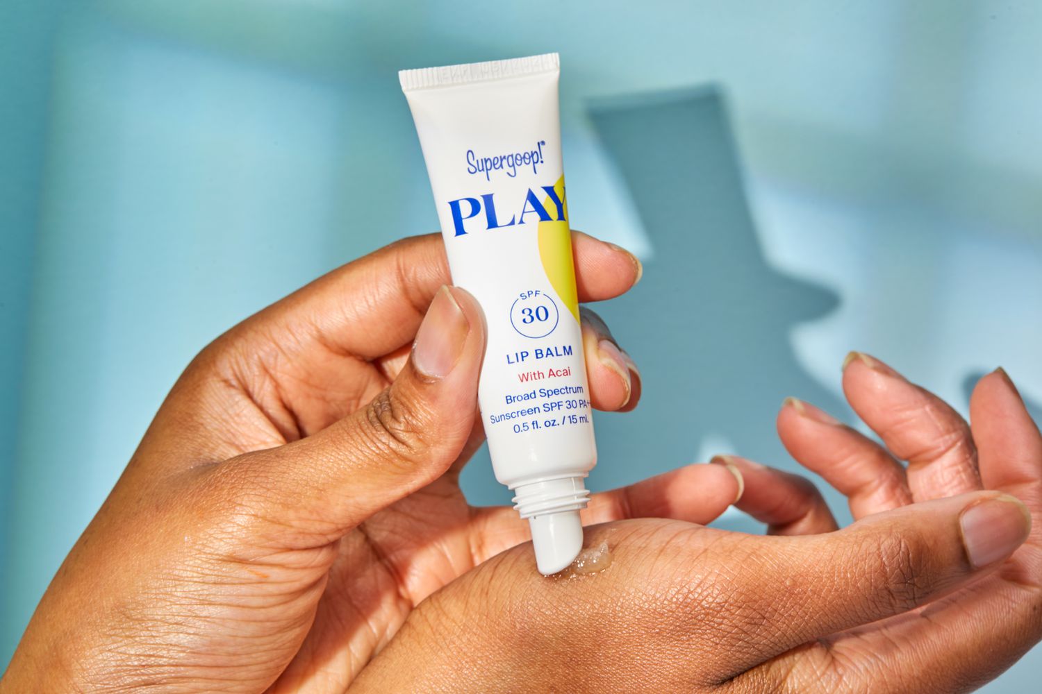 Person's hand squeezing Supergoop! PLAY Lip Balm SPF 30 on their hands