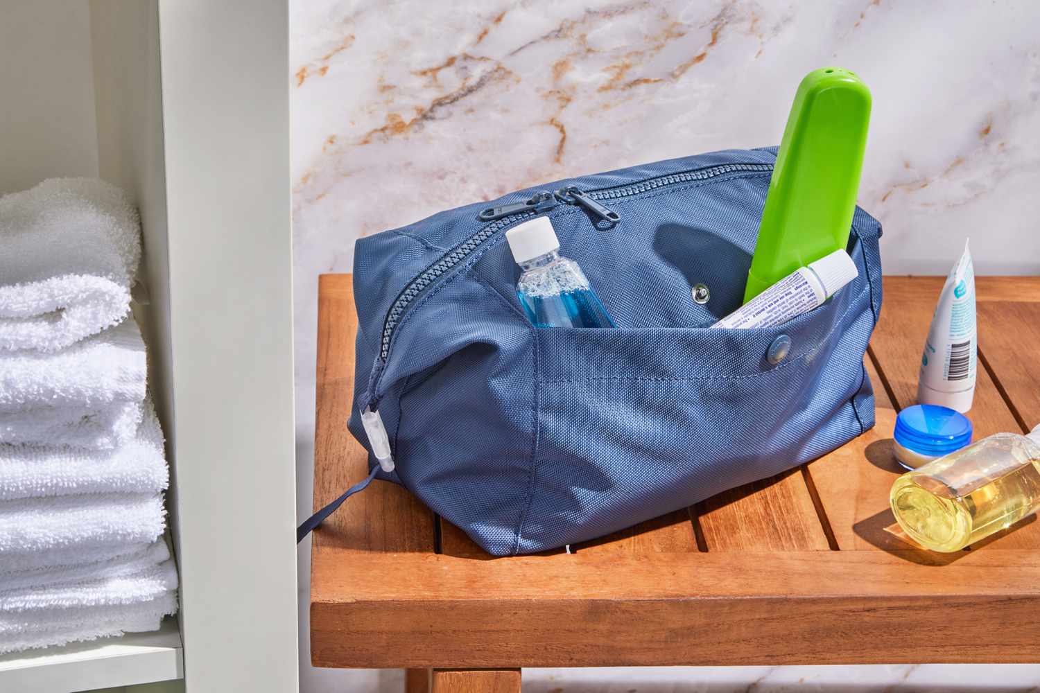 Dare to Roam Steward Dopp Kit on top of a wooden table with items sticking out from the side pocket