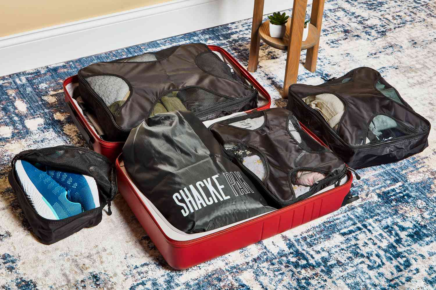 Shacke Pak 5 Set Packing Cubes displayed in an open suitcase on a blue rug