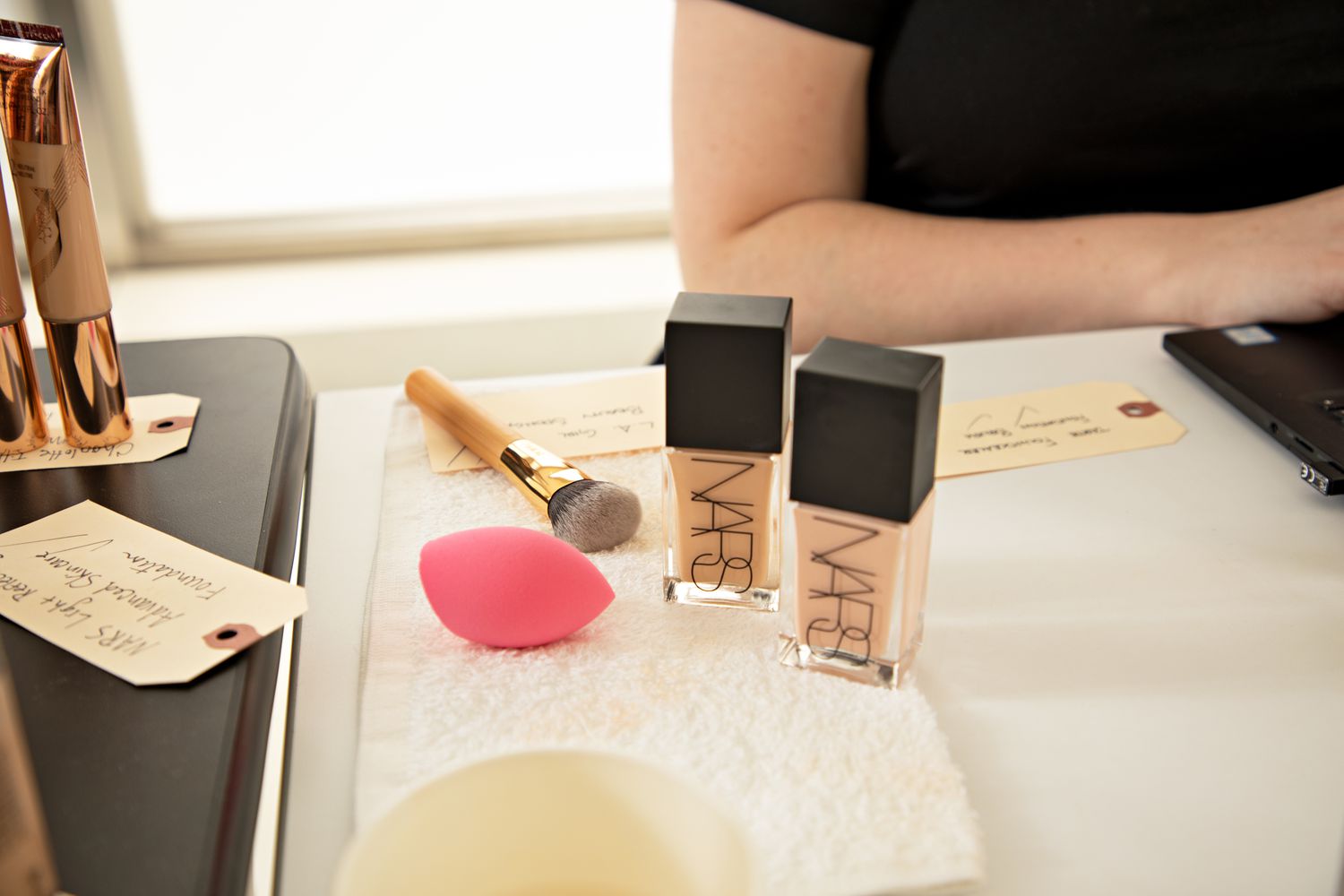 Tarte Foundcealer Foundation Brush laying on table next to cosmetics and person's arm