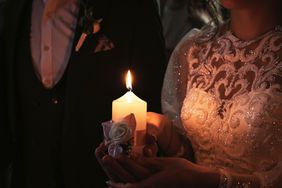 The bride and groom hold a lighted candle on the wedding day