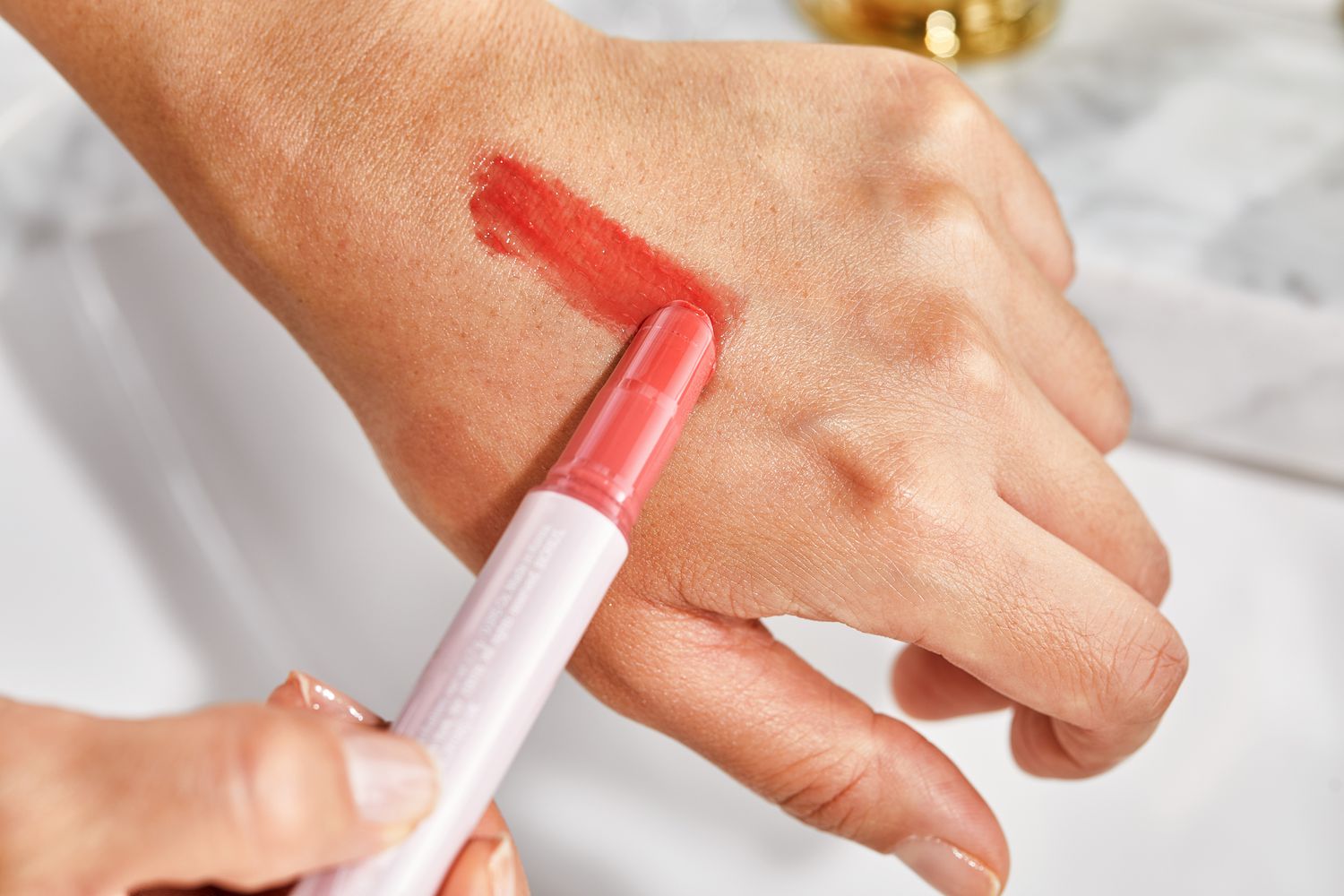 Close up of a person applying tarte Maracuja Juicy Lip Balm to the back of their hand