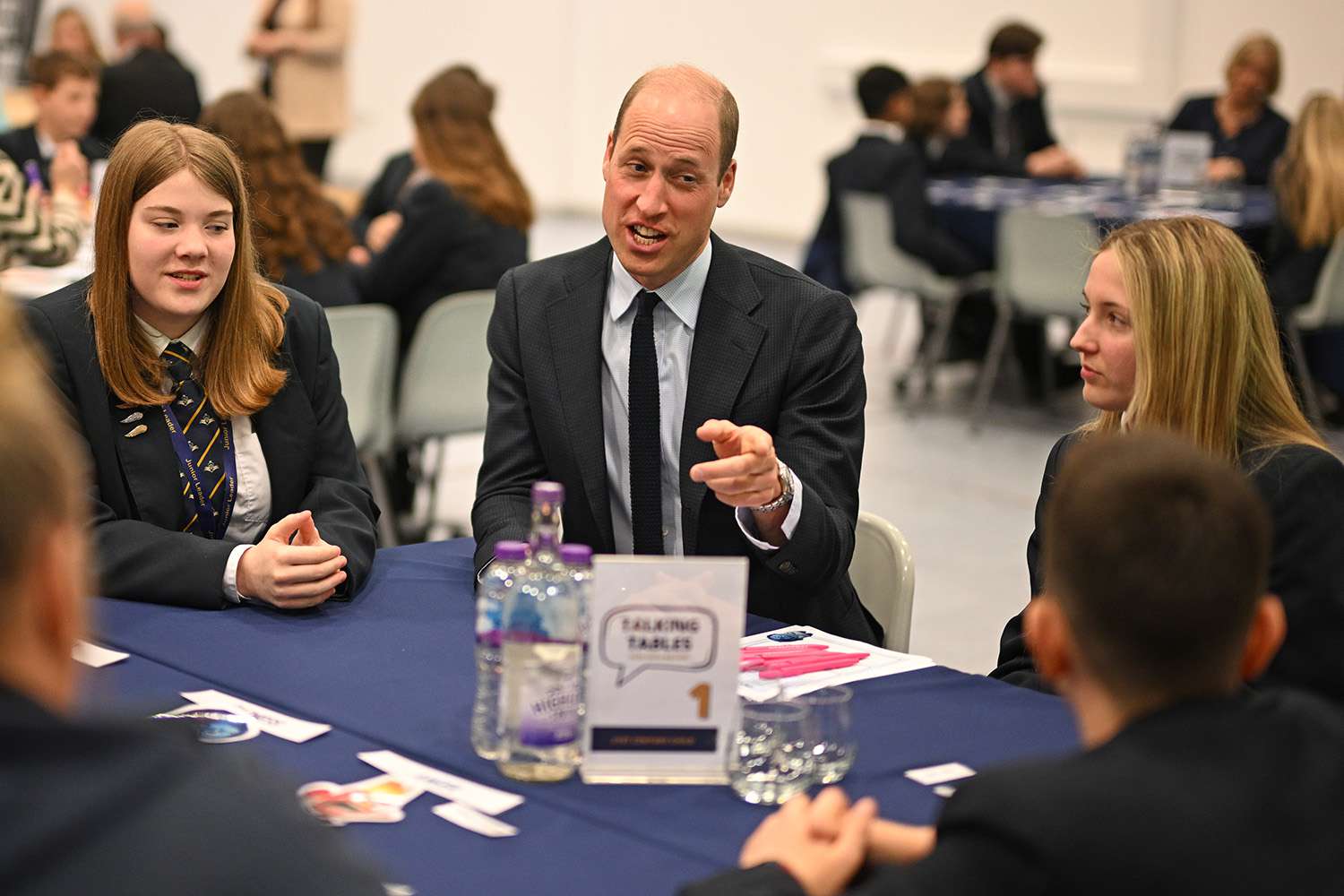 Prince William, Prince of Wales speaks with students using the "Talking Tables" initiative, during a visit to St. Michael's Church of England High School in Rowley Regis