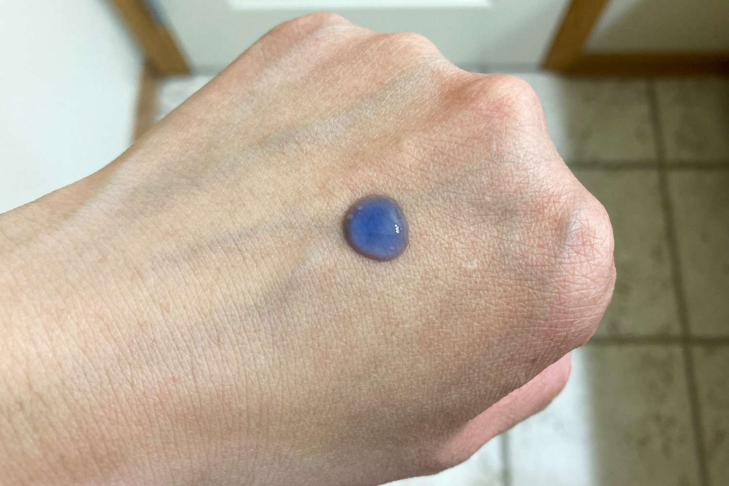 A small drop of The Ordinary Multi-Peptide + Copper Peptides 1% Serum on the back of a hand