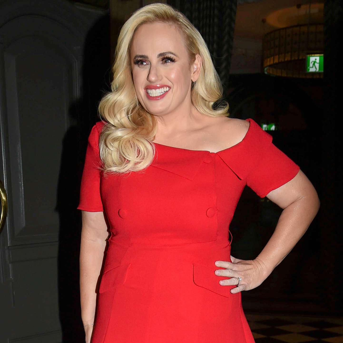 Rebel Wilson turns heads as she steps out of a Manchester hotel, showcasing her chic style in a striking red dress.