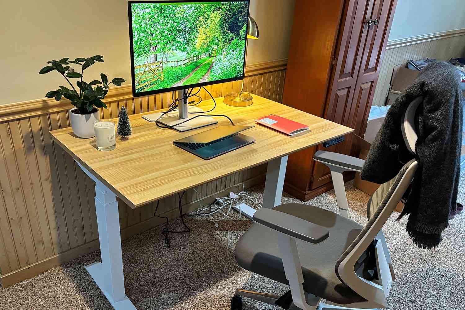 The Branch Standing Desk set up for use in person's home with desktop, laptop, chair, notebook and decor