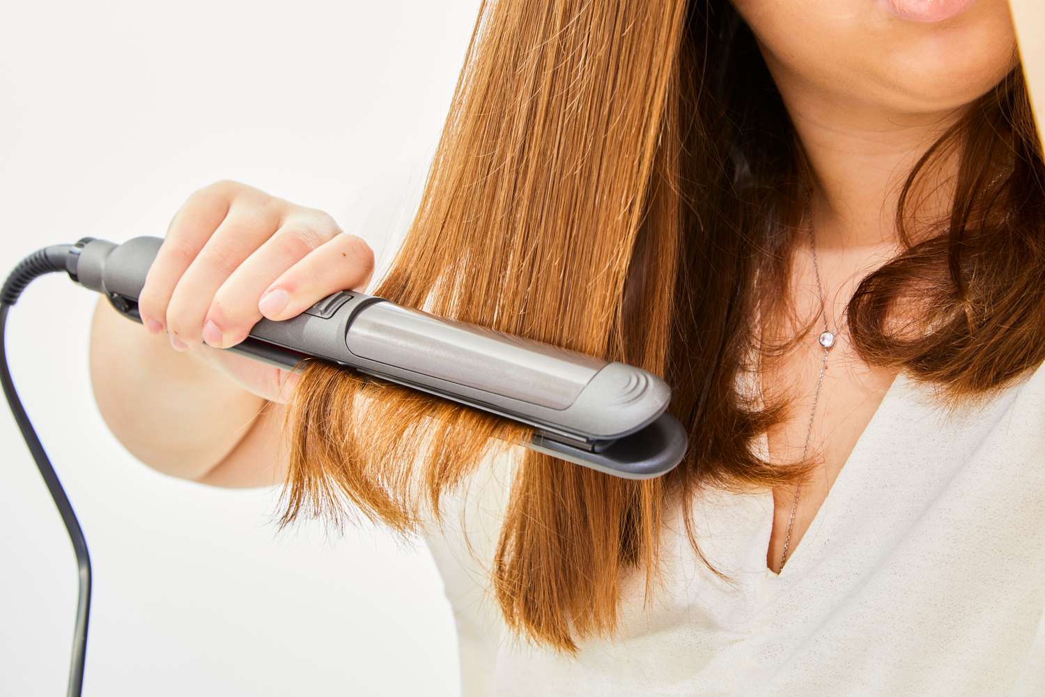 person straightens hair after using Amika Blockade Heat Defense Serum