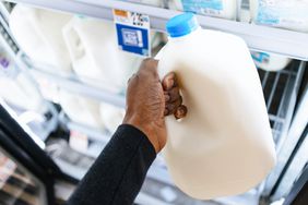 Close-up of someone picking up a gallon of milk at supermarket