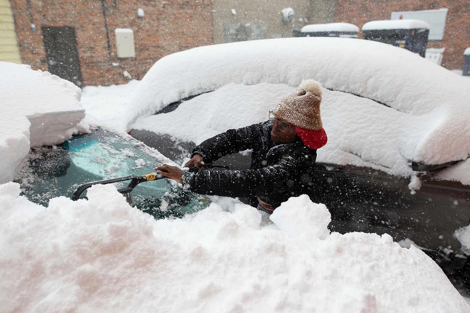 Zaria Black, 24, from Buffalo, clears off her car as snow falls, in Buffalo, N.Y. A dangerous lake-effect snowstorm paralyzed parts of western and northern New York, with nearly 2 feet of snow already on the ground in some places and possibly much more on the way