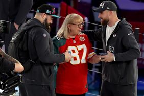 Mother Donna Kelce (C) gives cookies to her son's Jason Kelce (L) #62 of the Philadelphia Eagles and Travis Kelce (R) #87 of the Kansas City Chiefs during Super Bowl LVII Opening Night presented by Fast Twitch at Footprint Center on February 06, 2023 in Phoenix, Arizona. 