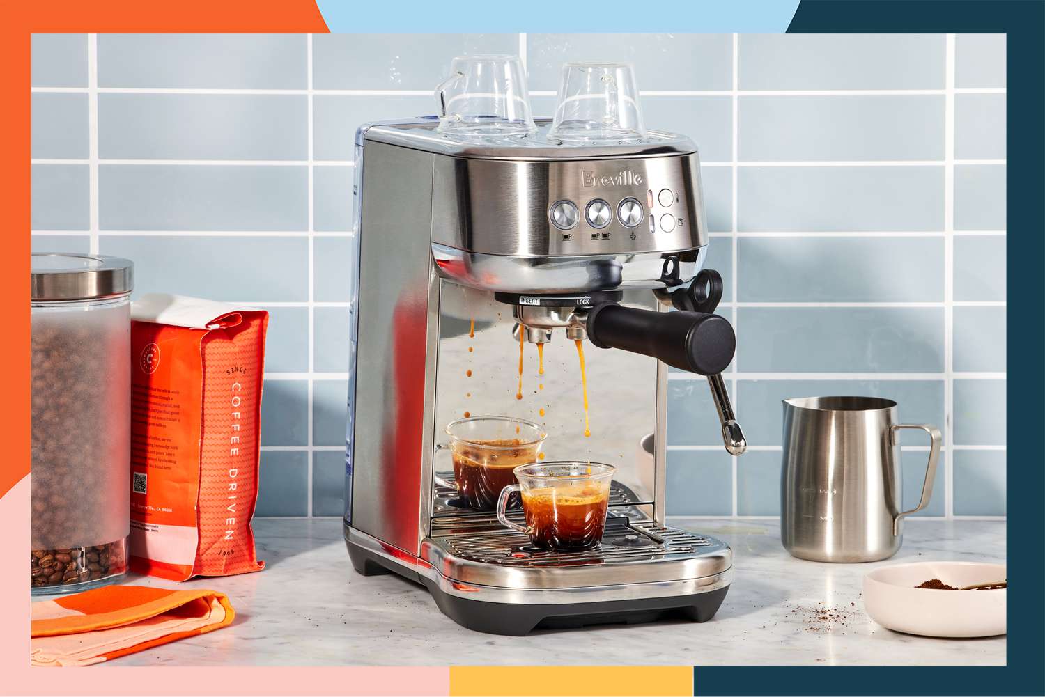 The Breville Bambino Plus Espresso Machine on a kitchen counter next to coffee beans. 