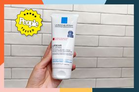 Hand holding La Roche-Posay Lipikar Soothing Relief Eczema Cream in front of a white tile wall