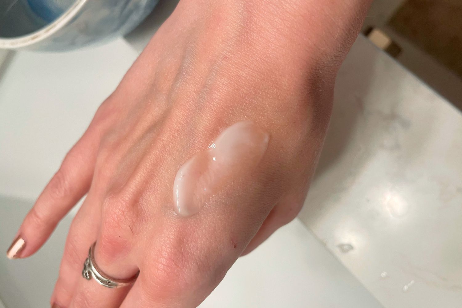 A hand over a sink with a small amount of the SkinFix Barrier Triple Lipid Collagen Niacinamide Activating Serum on it