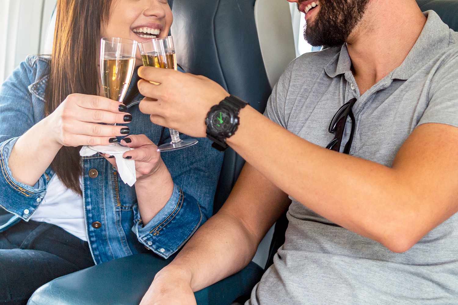 Photo of a young couple inside the airplane. and toasting.