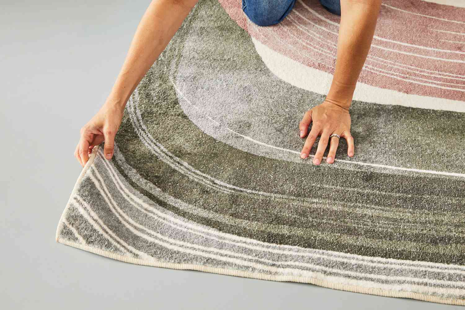 A person adjusting the West Elm Waterfall Washable Rug