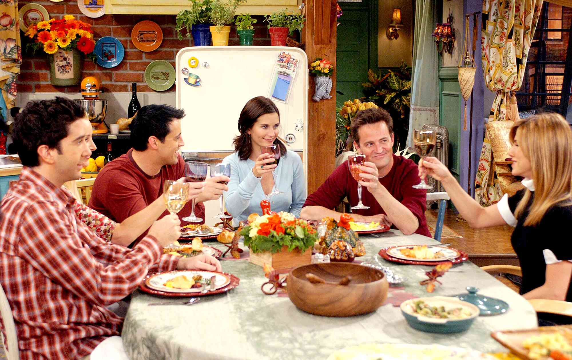 Cast of 'Friends' sitting around the table in Monica and Rachel's apartment at Thanksgiving