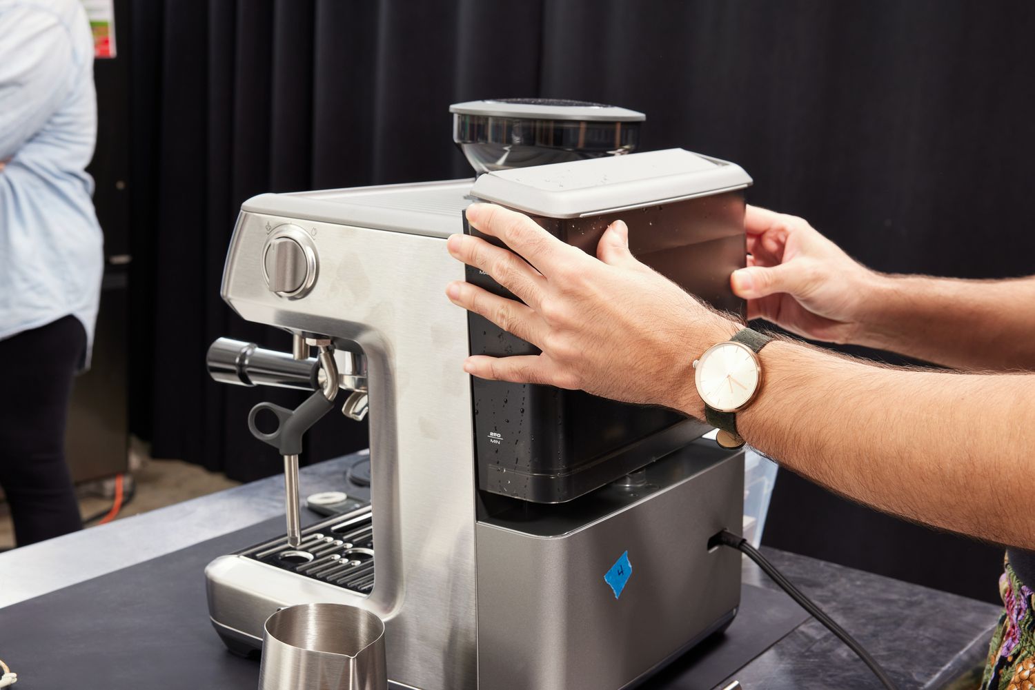 A person putting the water tank onto the back of the Breville Barista Express Impress.