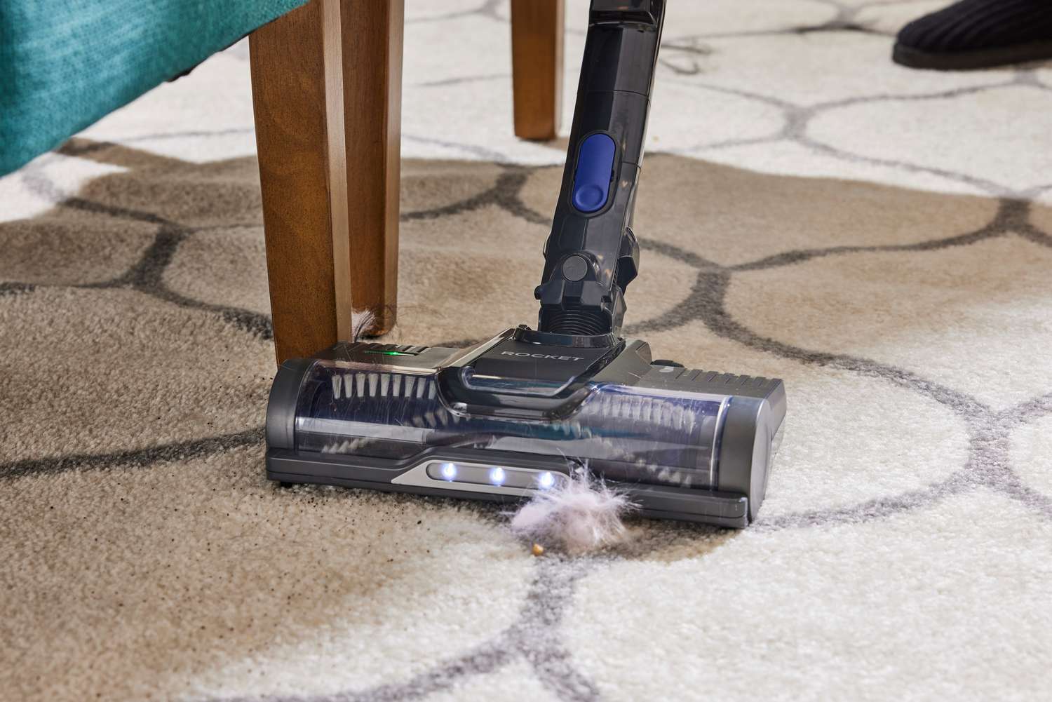 A close-up of his Shark Pet Cordless Stick Vacuum with XL Dust Cup cleaning a rug