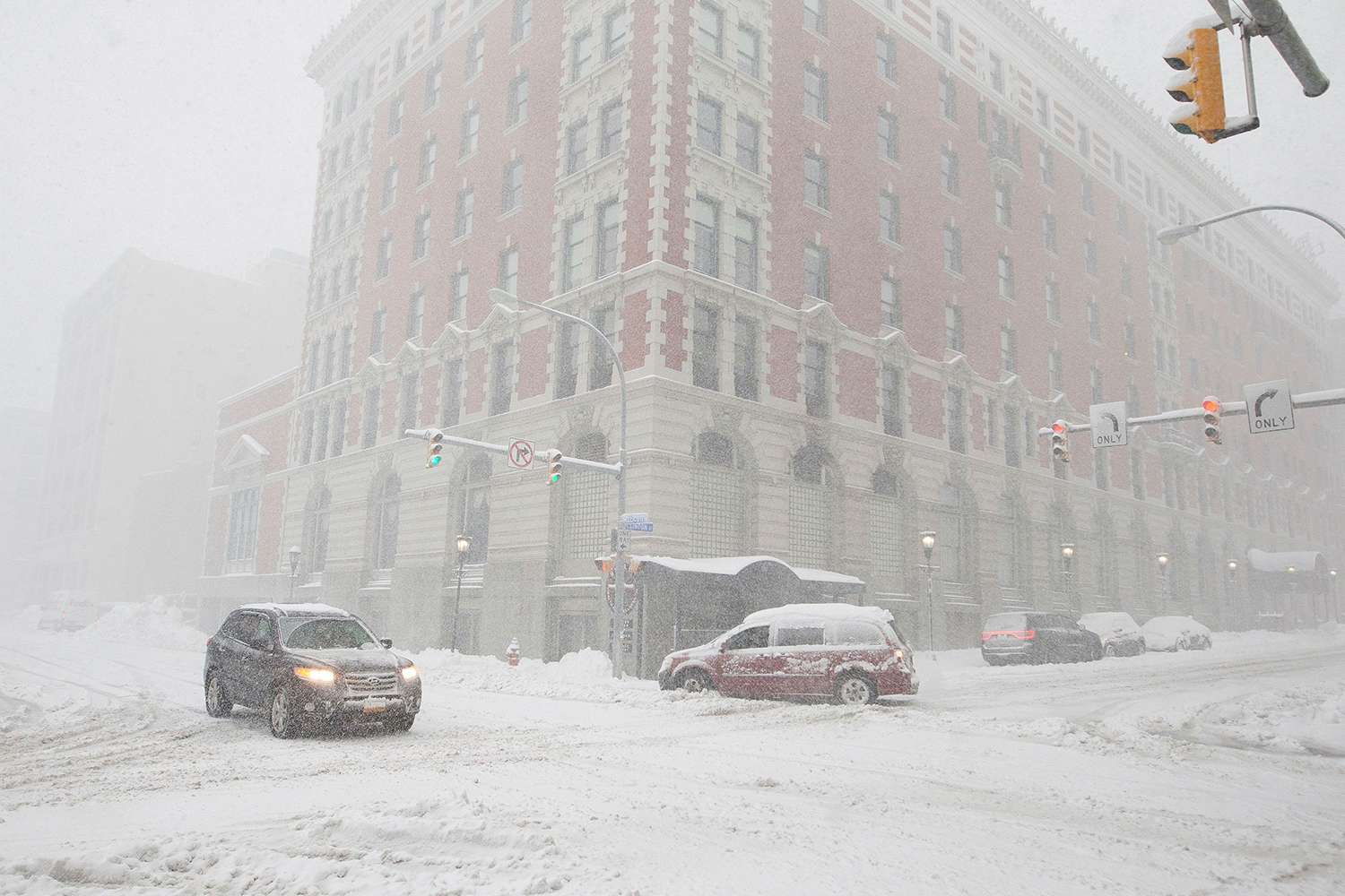 Cars drive along Ellicott Street as snow falls, in Buffalo, N.Y. A dangerous lake-effect snowstorm paralyzed parts of western and northern New York, with nearly 2 feet of snow already on the ground in some places and possibly much more on the way