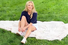 Reese Witherspoon wearing white shorts while sitting on a blanket on the grass