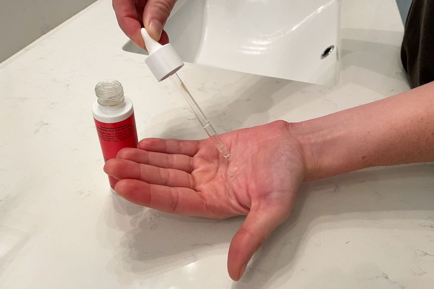 Hand using dropper to dispense Yes To Grapefruit Daily Brightening Serum onto palm