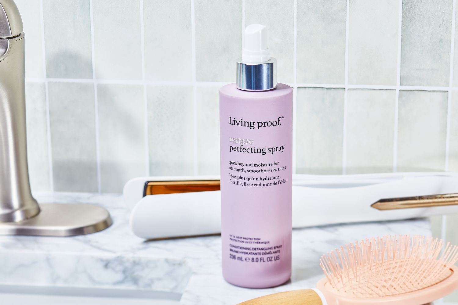 Living Proof Restore Perfecting Spray sits on counter top with hair styling tools