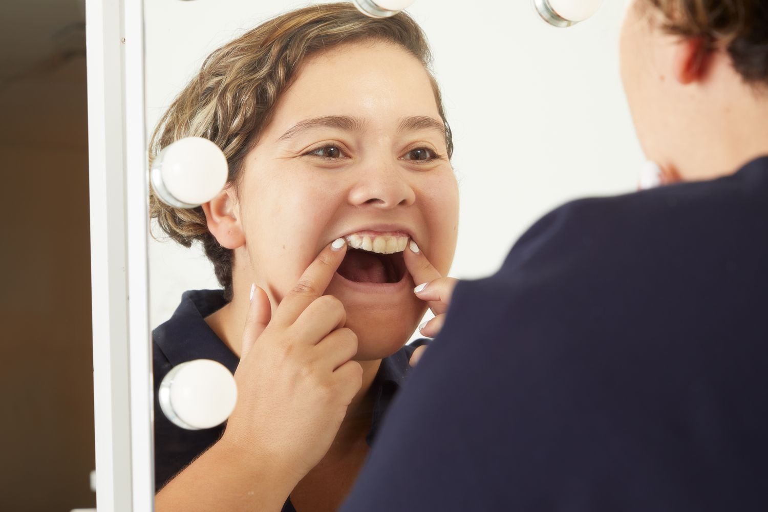 Person applying Crest 3D Whitestrips Sensitive Teeth Whitening Kit to upper teeth in mirror
