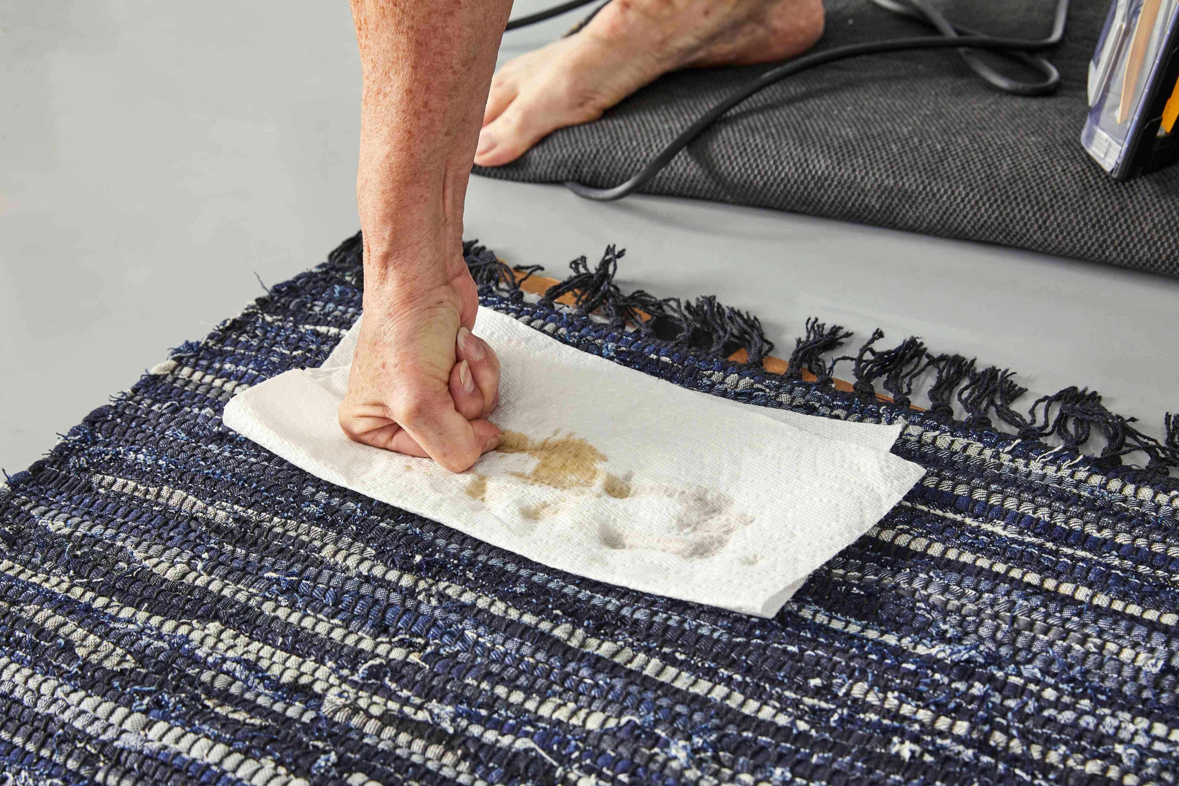 A person pressing down on a paper towel to clean a spill on the Revival Bootcut Washable Rug