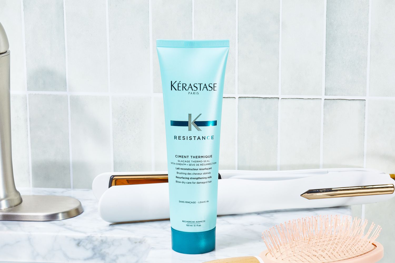 Kerastase RÃ©sistance Ciment Thermique Blow Dry Primer sits on bathroom counter with hair styling tools
