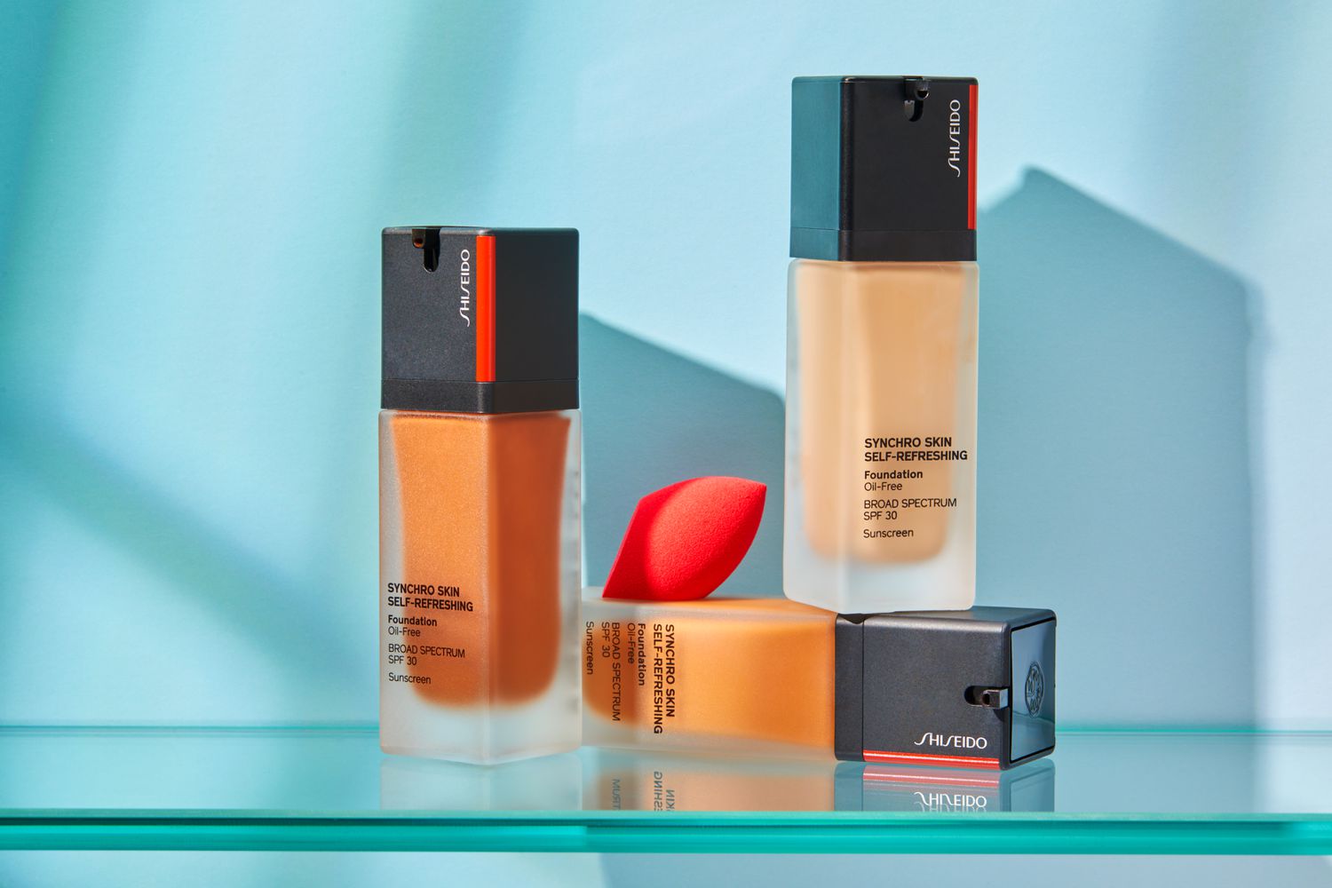 three shades of Shiseido Synchro Skin Self-Refreshing Foundation and makeup sponge on glass shelf