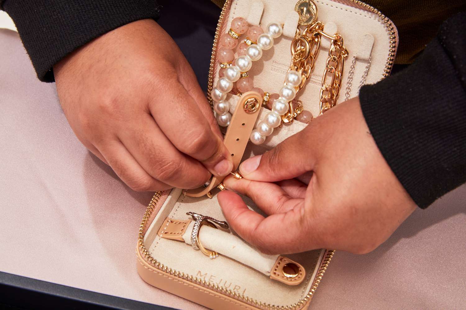 A person taking jewelry out of a Mejuri Jewelry Case