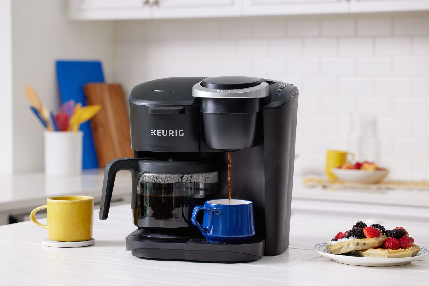 Keurig K-Duo Essentials Single Serve & Carafe Coffee Maker pouring coffee into a cup next to a plate of pancakes