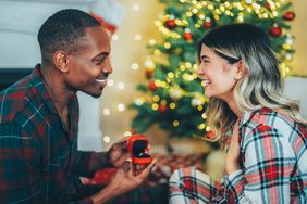 Young man surprising his girlfriend with engagement ring at Christmas
