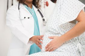 Mixed race doctor examining pregnant patient's belly