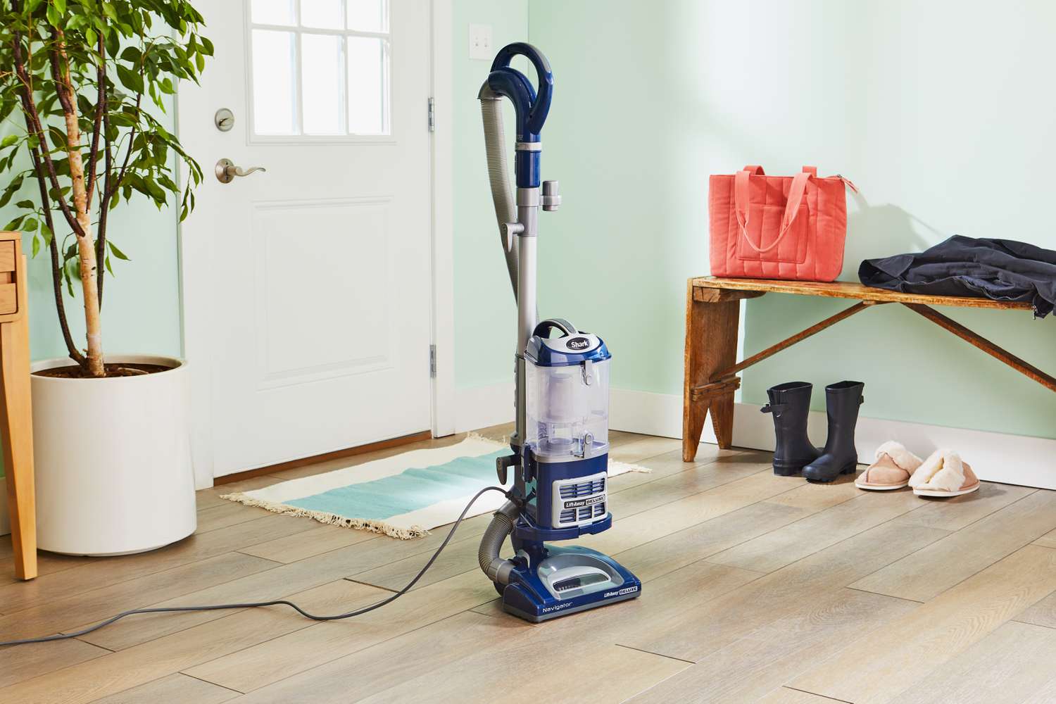 Shark NV360 Navigator Lift-Away Deluxe Upright Vacuum displayed in an entryway next to bench and plant